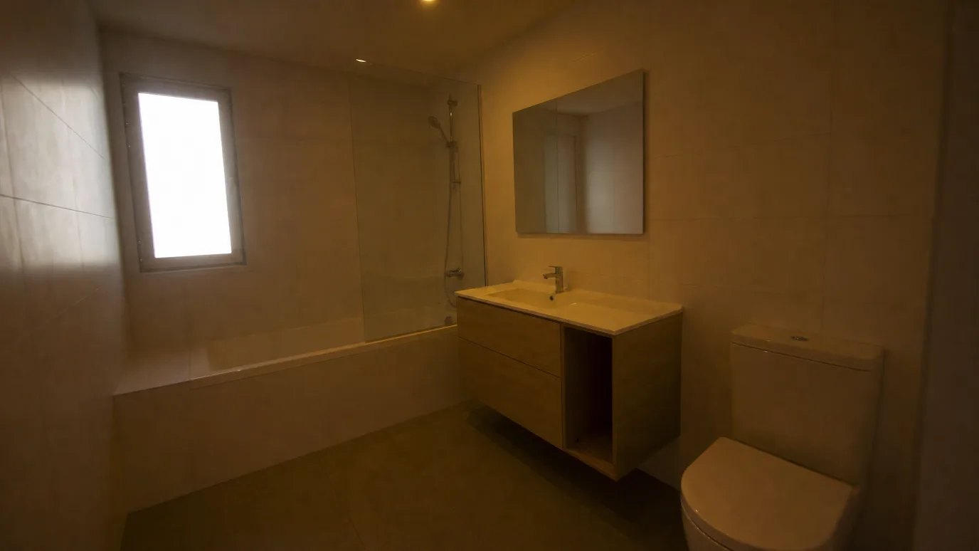 El mismo baño después de la mejora de foto — azulejo blanco neutro, luz clara y uniforme y la ventana recuperada — before